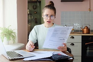 Young Woman Looking at Paperwork with a Shocked Expression